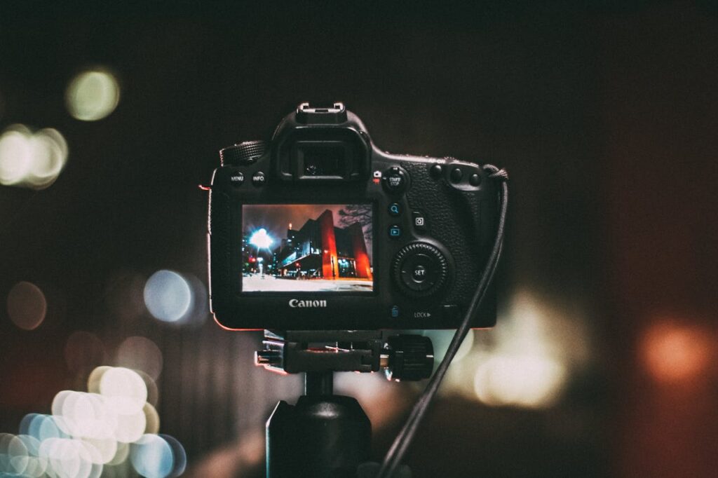 pexels-photo-243757 Close-up of a camera capturing a vibrant urban scene at night with a blurred bokeh background.