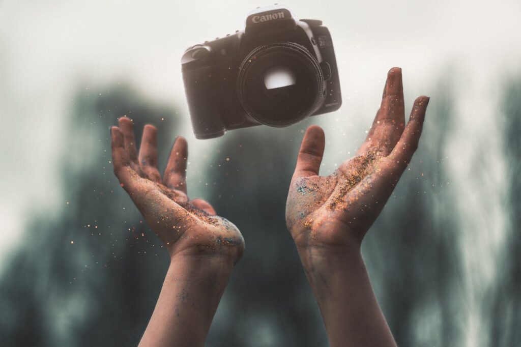 pexels-photo-986733 Hands tossing a DSLR camera with a magical sparkle effect in nature.